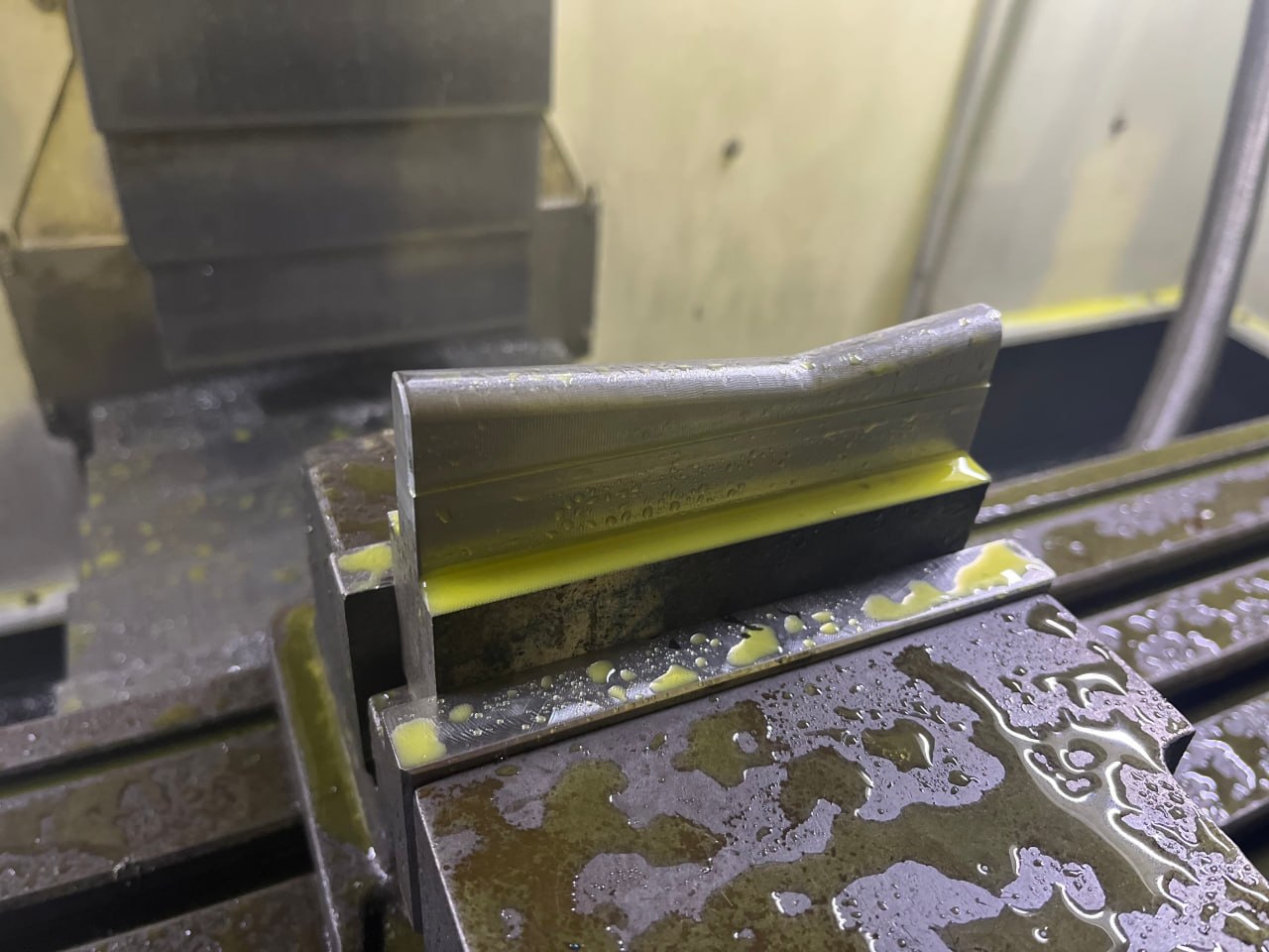 Aluminiumdetalj uppspänd i CNC-maskin med skärvätska